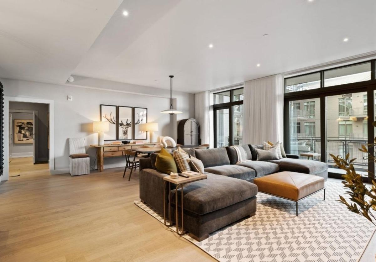 Bright, modern living room with a large sectional sofa and floor-to-ceiling windows